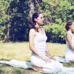 Two beautiful young women doing yoga class in nature.